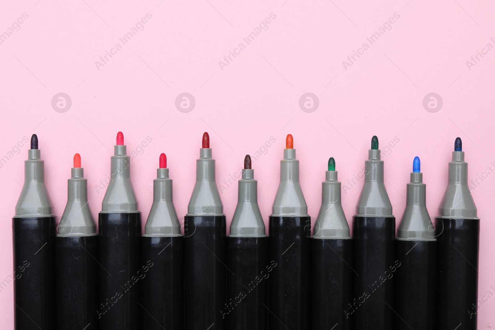 Photo of Colorful markers on light pink background, top view. Space for text