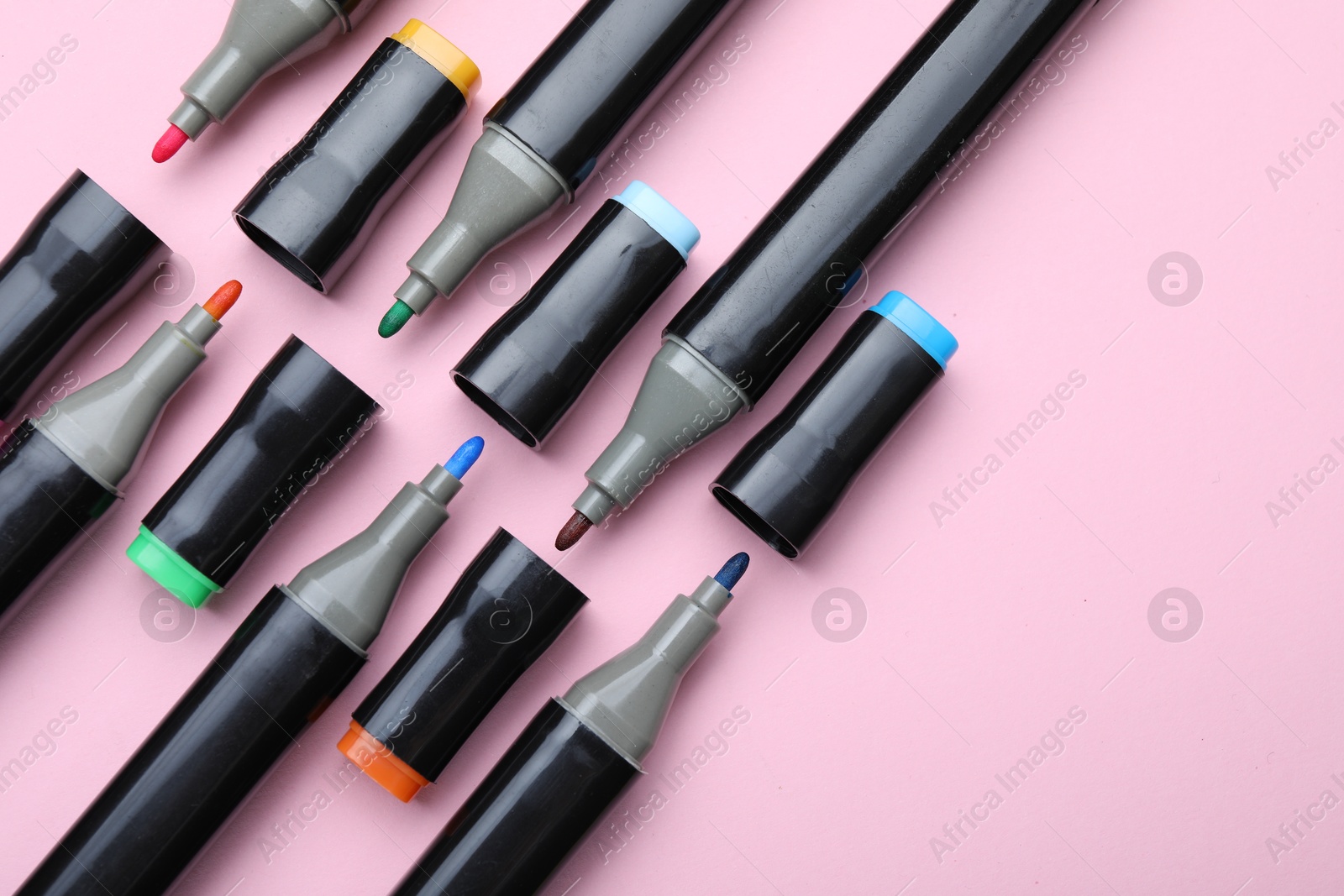 Photo of Colorful markers on light pink background, flat lay