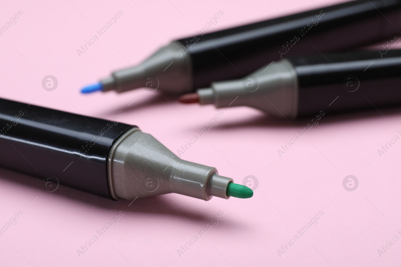 Photo of Colorful markers on light pink background, closeup