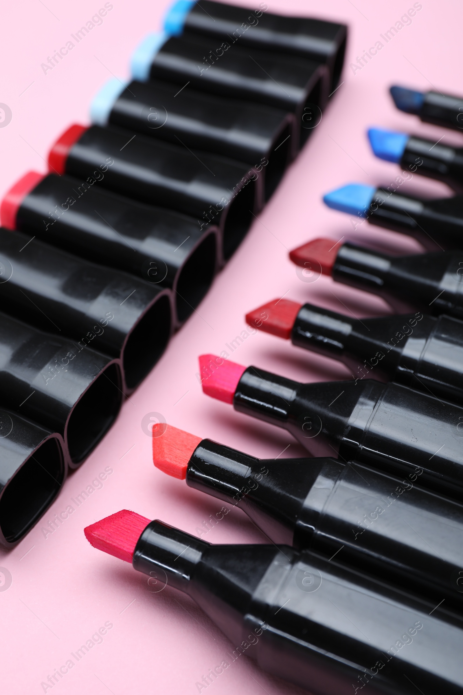 Photo of Colorful markers on light pink background, closeup