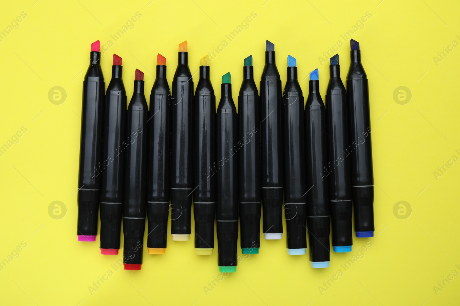 Photo of Colorful double sided markers on yellow background, top view