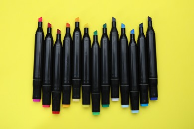 Photo of Colorful double sided markers on yellow background, top view