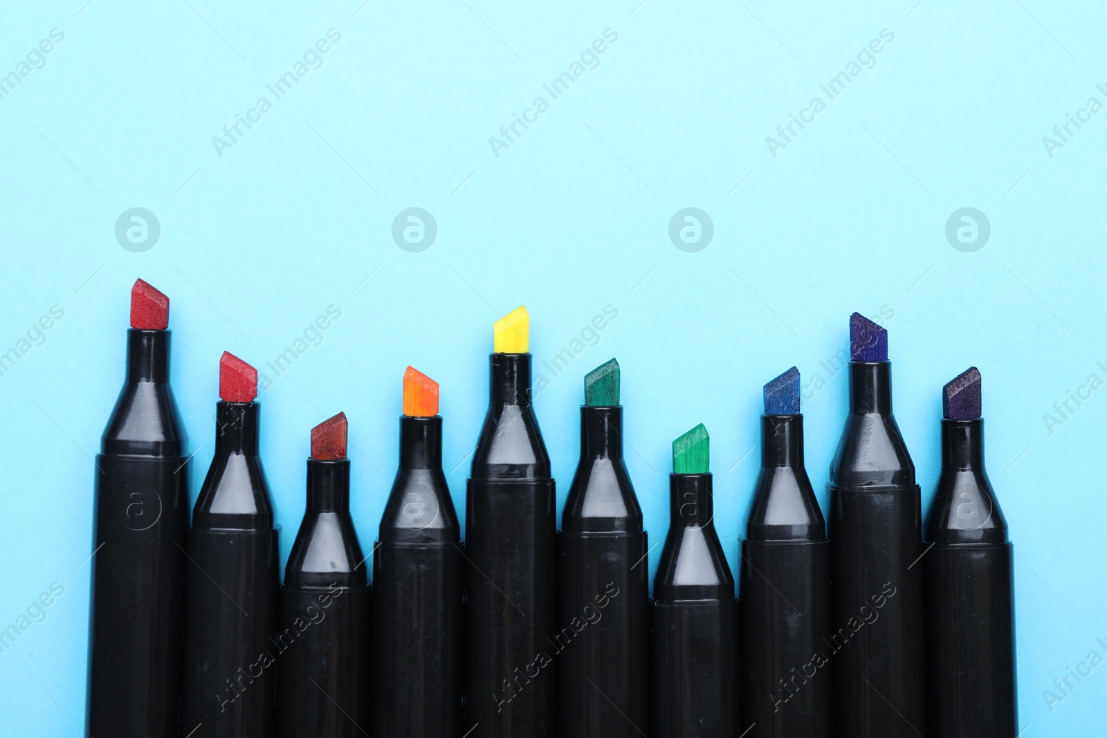 Photo of Colorful markers on light blue background, top view. Space for text