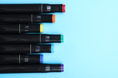 Photo of Colorful markers on light blue background, top view. Space for text