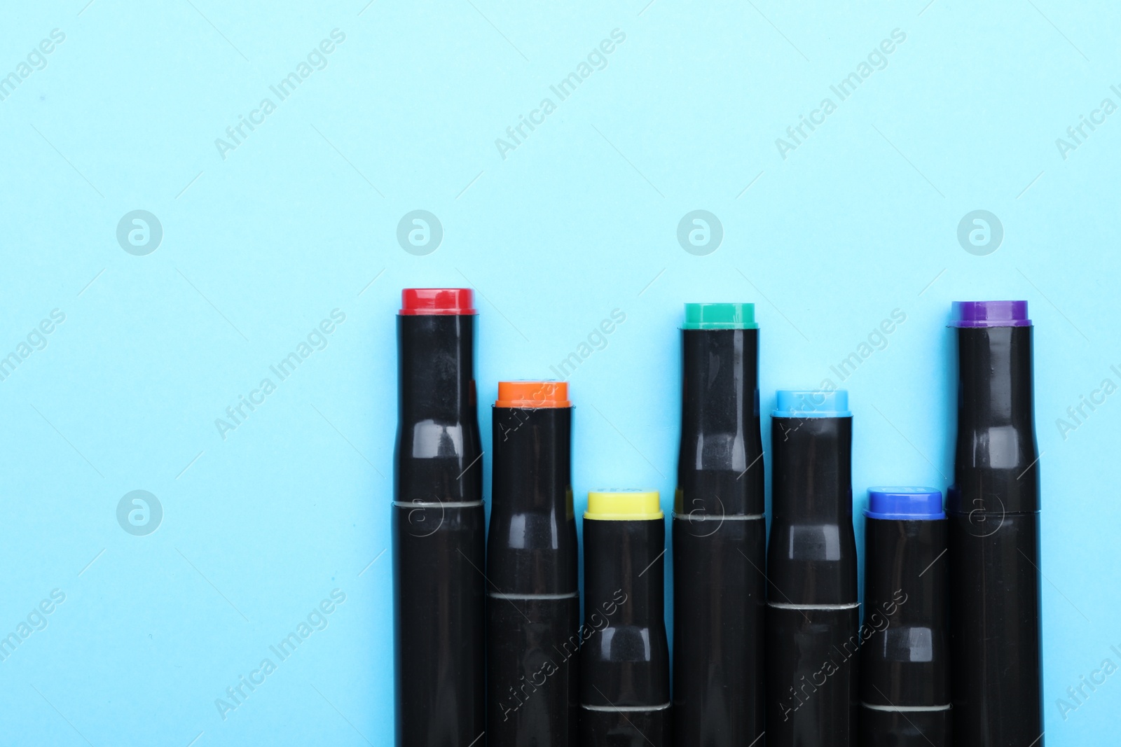 Photo of Colorful markers on light blue background, top view. Space for text