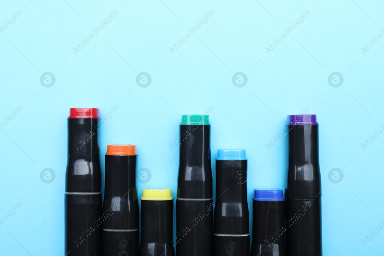 Photo of Colorful markers on light blue background, top view. Space for text