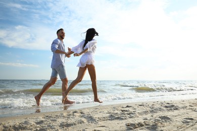 Photo of Happy young couple running together on beach