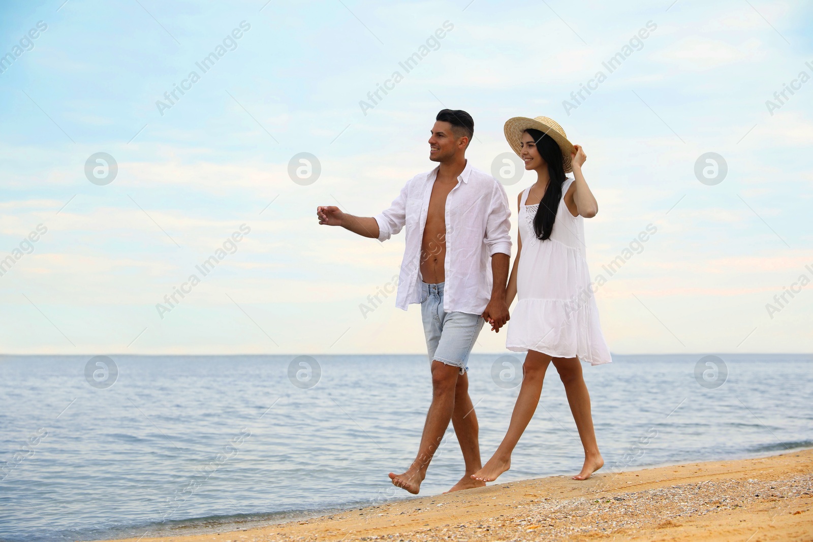 Photo of Lovely couple holding hands while walking on beach