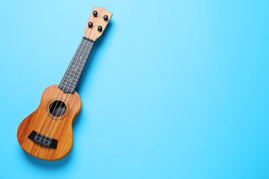 Photo of One ukulele on light blue background, top view. Space for text