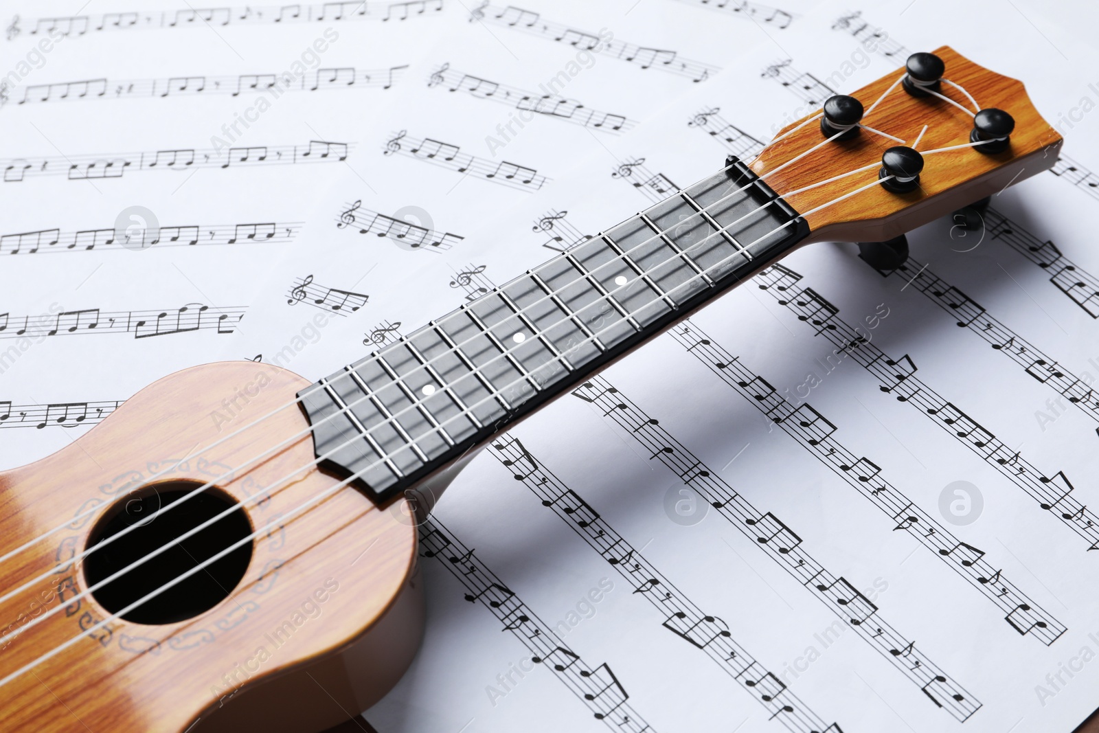 Photo of One ukulele on music sheets, closeup view