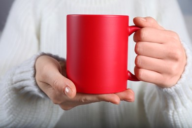 Photo of Woman holding blank red ceramic mug, closeup. Mockup for design