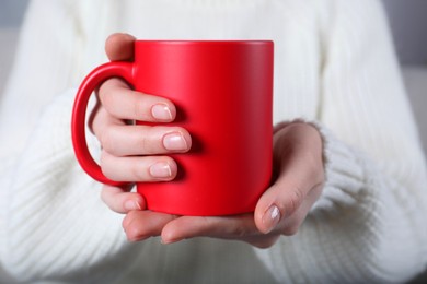 Photo of Woman holding blank red ceramic mug, closeup. Mockup for design