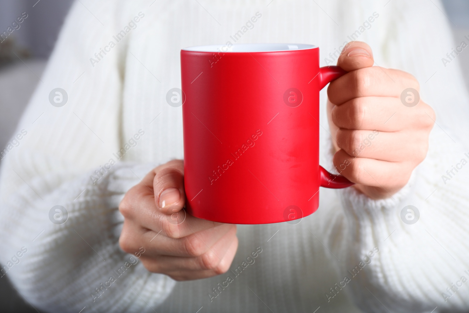 Photo of Woman holding blank red ceramic mug, closeup. Mockup for design