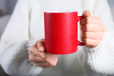 Photo of Woman holding blank red ceramic mug, closeup. Mockup for design