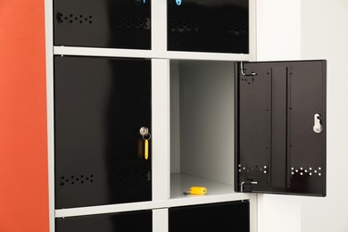 Photo of Modern lockers with keys on coral background, closeup