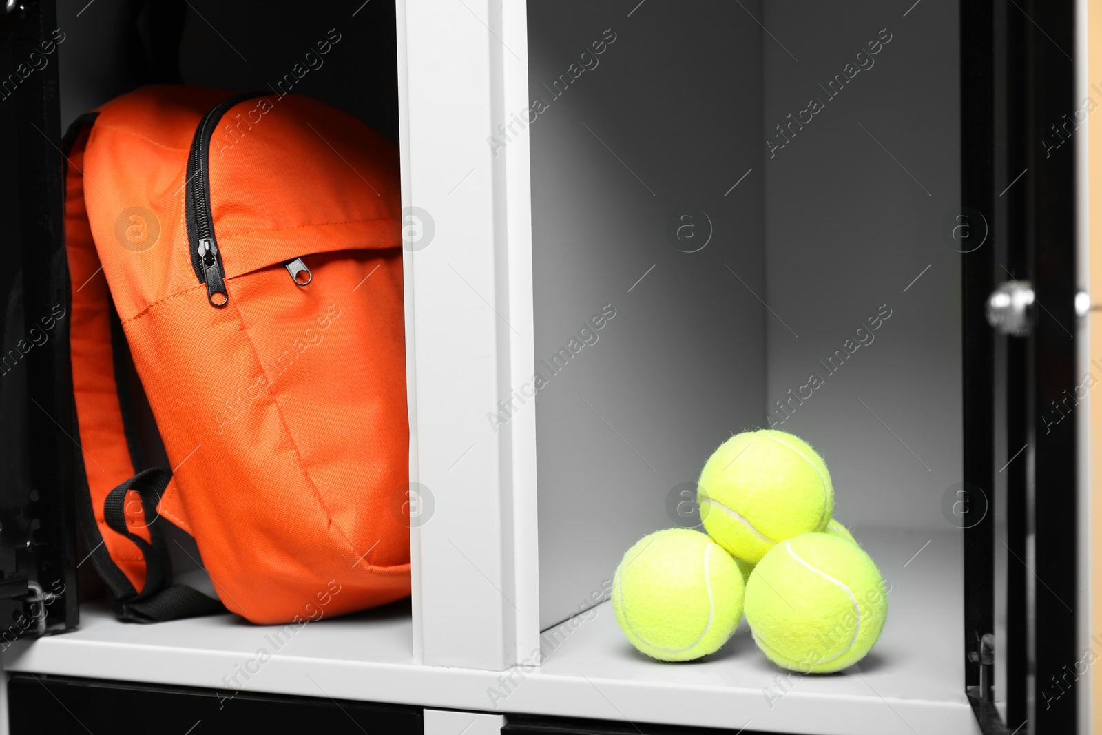 Photo of Open lockers with backpack and tennis balls, closeup