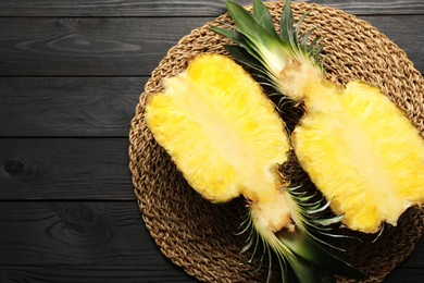 Photo of Halves of ripe pineapple on black wooden table, top view. Space for text