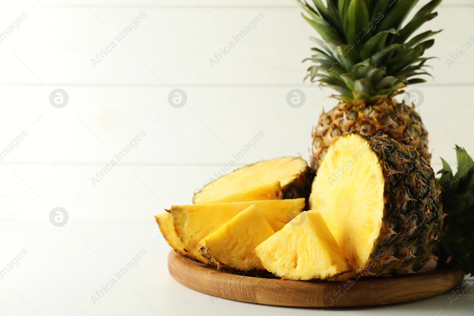 Photo of Whole and sliced fresh ripe pineapples on white table, space for text