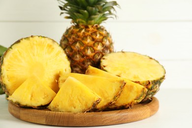 Whole and sliced fresh ripe pineapples on white table, closeup