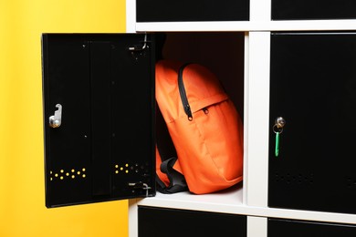 Open locker with backpack on orange background