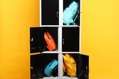 Photo of Lockers with different backpacks on orange background