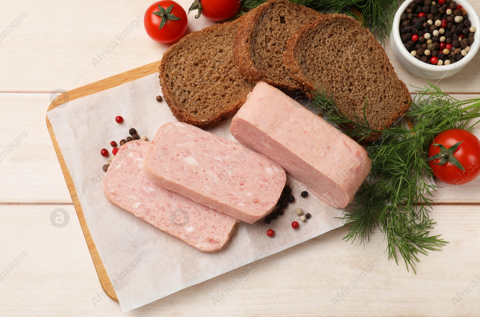 Photo of Pieces of tasty canned meat, tomatoes, peppercorns, dill and bread on light wooden table, flat lay