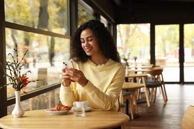 Woman using smartphone during her coffee break in cafe