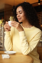 Woman enjoying her aromatic coffee at table in cafe