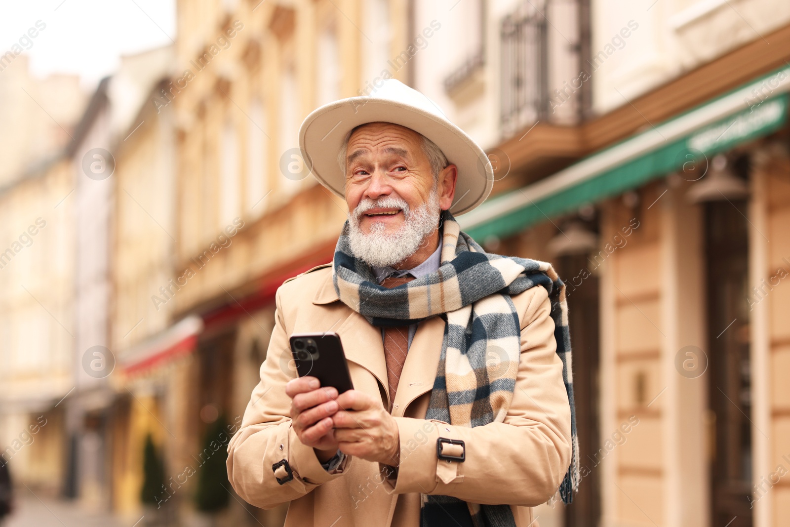 Photo of Stylish senior man with smartphone on city street