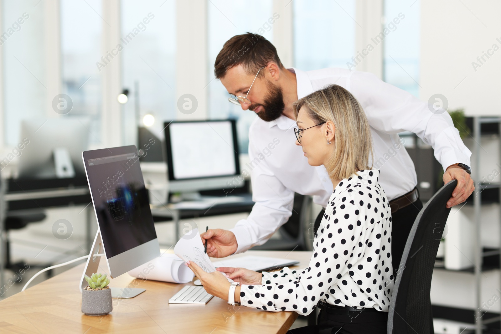 Photo of Technicians making digital engineering drawing on computer at desk in office