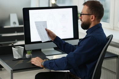 Photo of Technician making digital engineering drawing on computer at desk in office