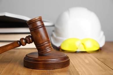 Photo of Accident at work concept. Gavel, books and construction worker's protective gear on wooden table, selective focus