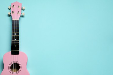 Photo of One ukulele on light blue background, top view. Space for text