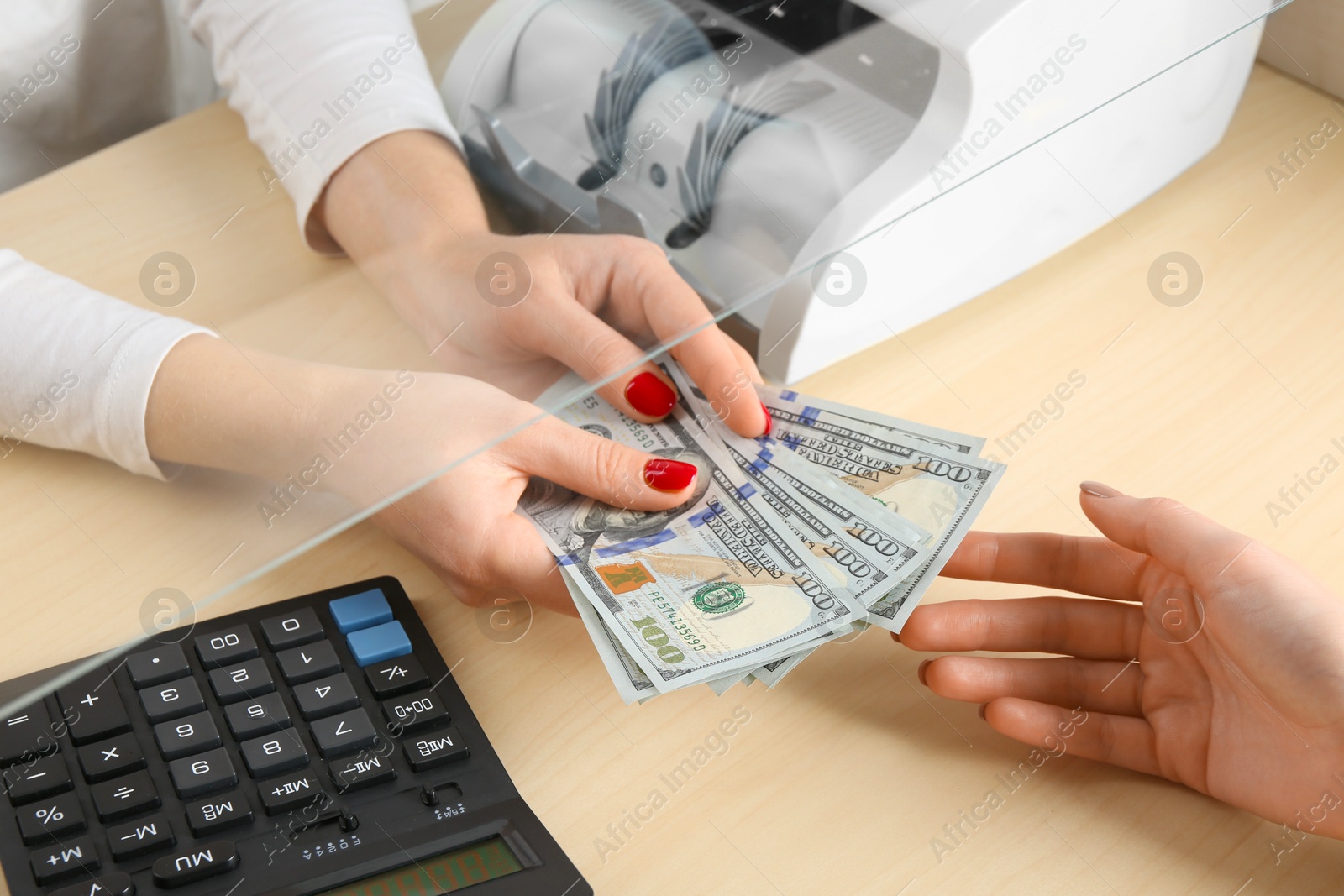 Photo of Cashier giving dollar banknotes to client at table in money exchange, closeup