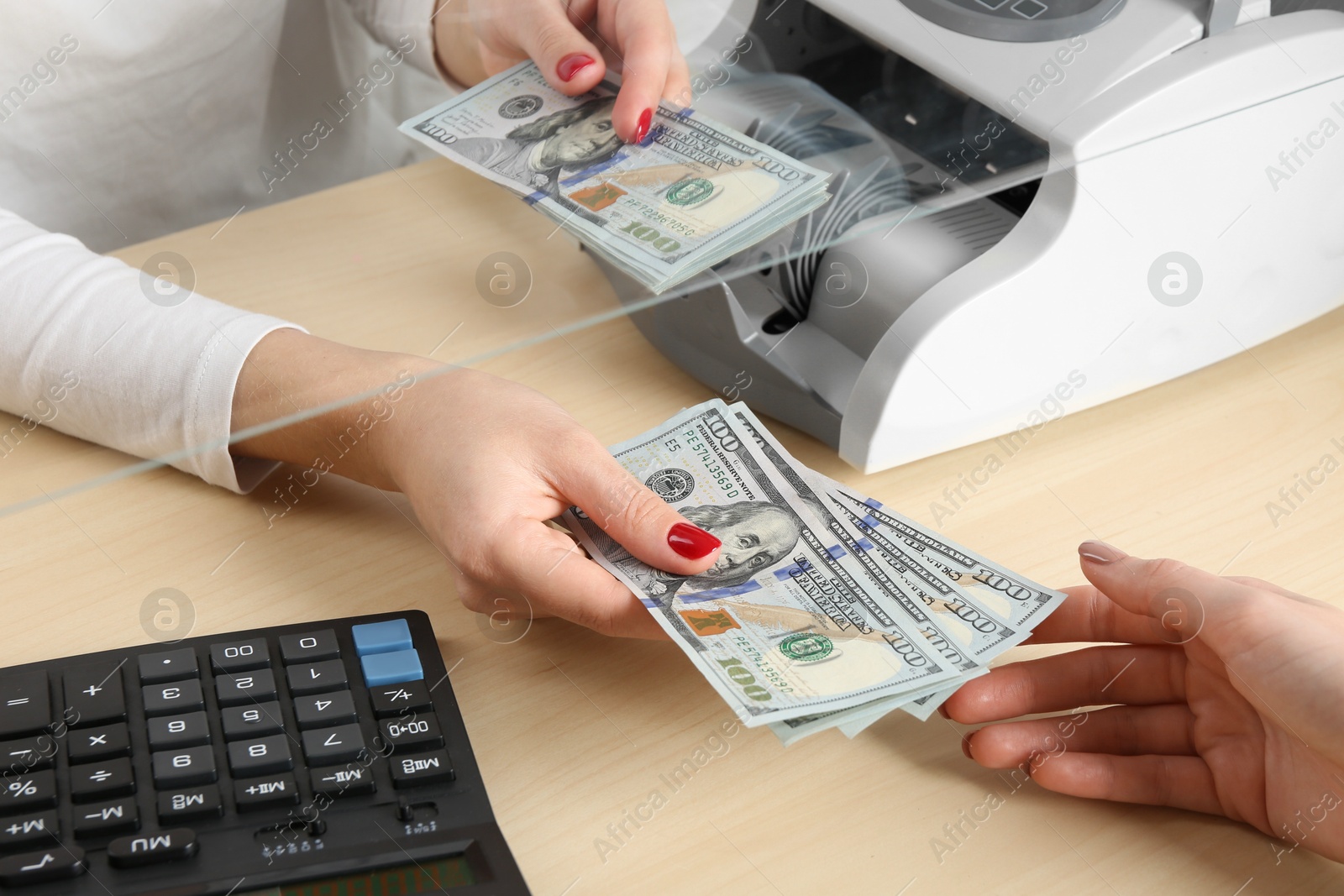 Photo of Cashier giving dollar banknotes to client at table in money exchange, closeup