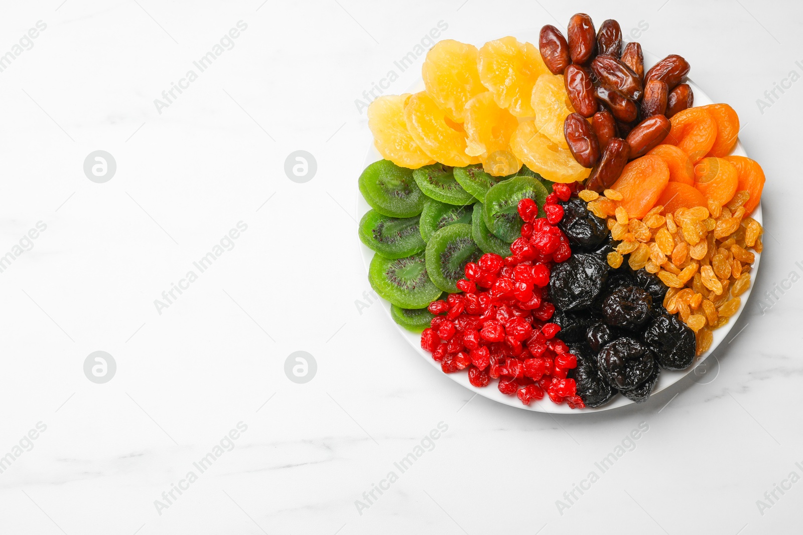 Photo of Mix of different dried fruits on white marble table, top view. Space for text