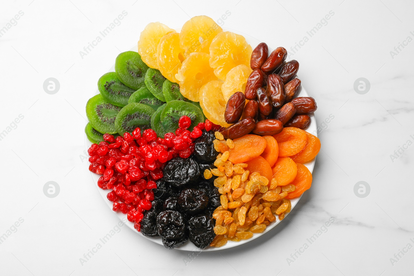 Photo of Mix of different dried fruits on white marble table, top view