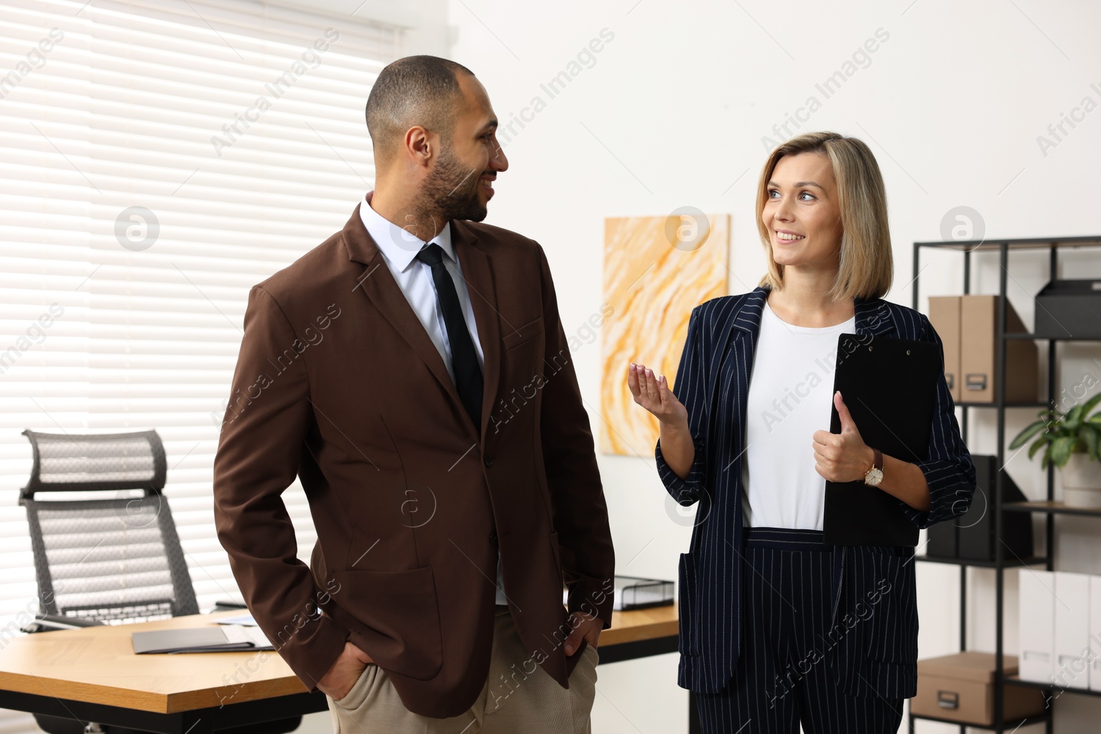 Photo of Happy coworkers talking in modern office. Working together