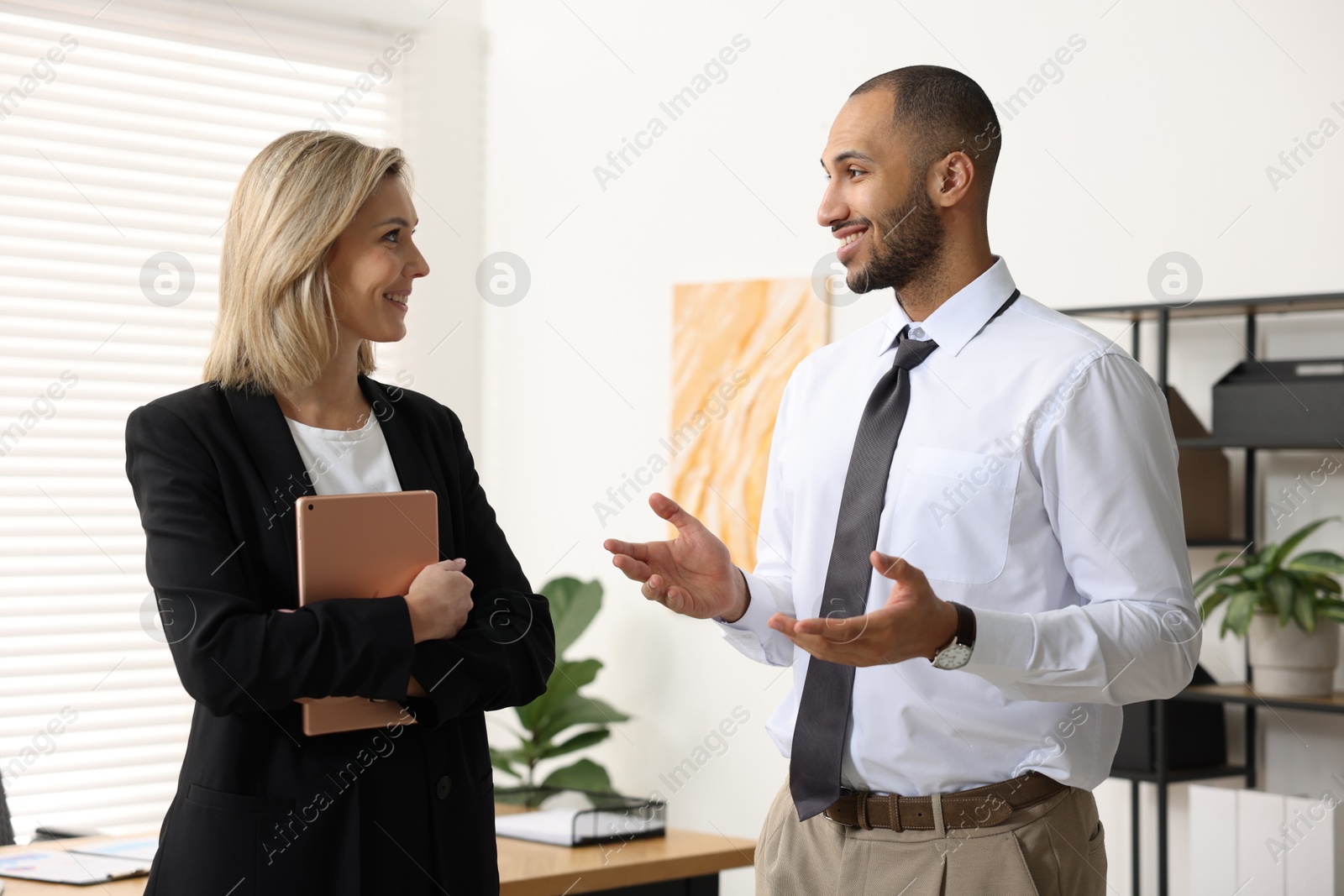 Photo of Happy coworkers talking in modern office. Working together