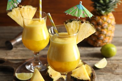 Photo of Tasty pineapple cocktail in glasses served on wooden table, closeup