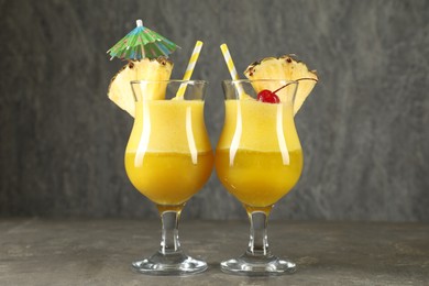 Photo of Tasty pineapple cocktail in glasses served on grey table