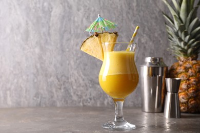 Photo of Tasty pineapple cocktail in glass served on grey table, space for text