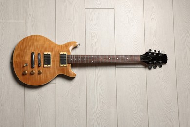 Photo of One modern electric guitar on light wooden background, top view