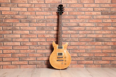 Photo of One modern electric guitar near brick wall