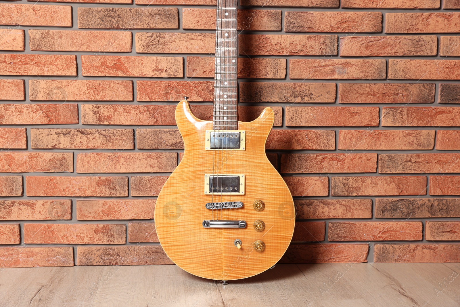 Photo of One modern electric guitar near brick wall