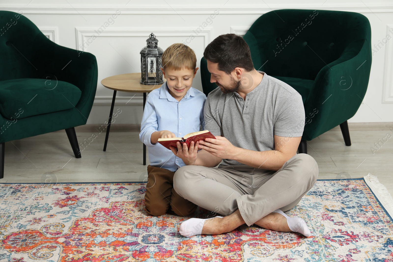 Photo of Muslim man and his son reading Quran at home