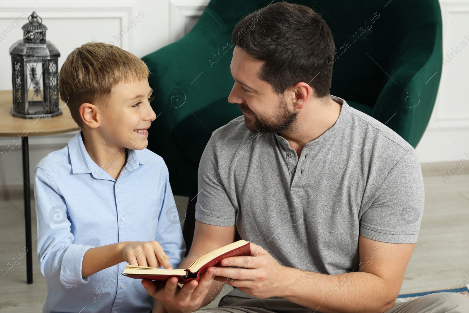 Photo of Muslim man and his son reading Quran at home