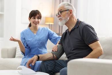 Photo of Nurse measuring senior man's blood pressure at home