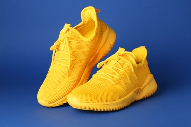 Photo of Pair of stylish yellow sneakers on blue background