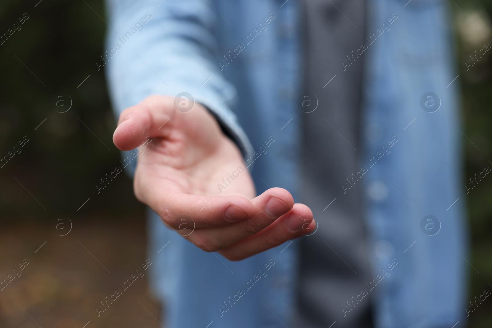 Photo of Offering help. Man reaching his hand outdoors, closeup